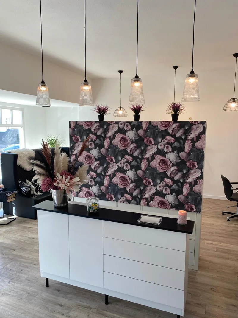Einblick bei CUT: heller Salon mit floralem Empfangstresen und warmen Pendelleuchten